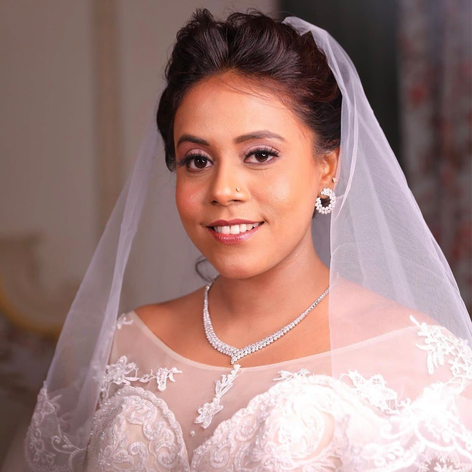 Bride in a white lace gown and sheer veil with a diamond necklace